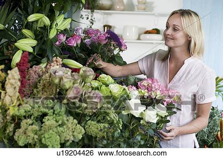 Stock Photograph - Woman florist in her shop, surrounded by an assortment of flowers. Fotosearch