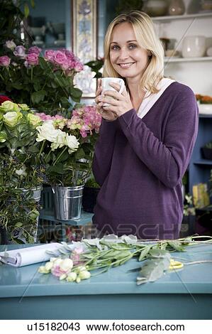 Stock Image - Woman florist in her shop, taking a break. Fotosearch