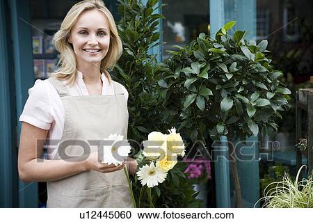 Woman florist or gardener holding some white flowers View Large Photo Image Stock Image - Woman florist or gardener holding some white flowers. Fotosearch