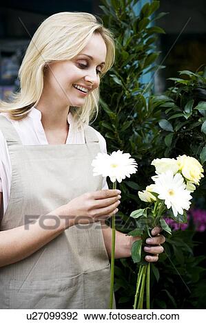 Stock Image - Woman florist or gardener holding some white flowers. Fotosearch