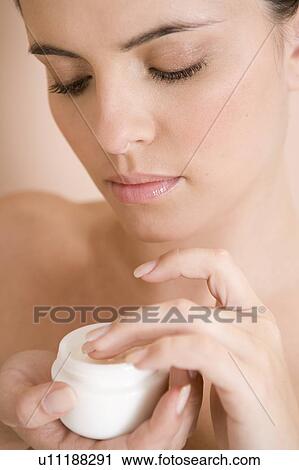 Stock Image - Woman holding a pot of moisturising cream. Fotosearch