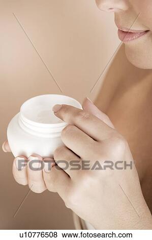 Stock Photo - Woman holding a pot of moisturising cream. Fotosearch