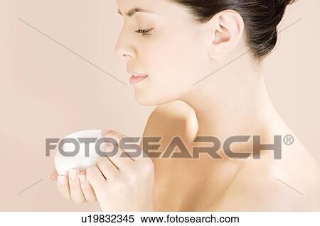 Stock Photography - Woman holding a pot of moisturising cream. Fotosearch