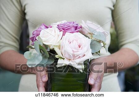 Stock Photograph - Woman holding a square vase of pink roses . Fotosearch