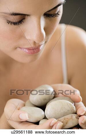 Stock Photo - Woman holding stones for hot stone therapy. Fotosearch