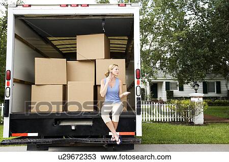 Woman moving home, sitting in the removal van and talking on her mobile phone View Large Photo Image Stock Image - Woman moving home, sitting in the removal van and talking on her mobile phone. Fotosearch