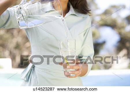 Woman pouring a glass of water View Large Photo Image Stock Photo - Woman pouring a glass of water. Fotosearch