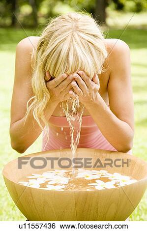 Stock Photograph - Woman splashing her face, in a tropical setting.. Fotosearch