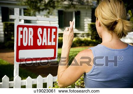 Woman standing by a for sale sign outside a family house, fingers crossed View Large Photo Image Stock Image - Woman standing by a for sale sign outside a family house, fingers crossed. Fotosearch