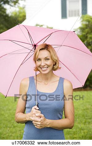 Stock Image - woman standing under pink umbrella. Fotosearch
