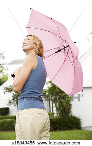 Stock Photography - woman standing under pink umbrella. Fotosearch