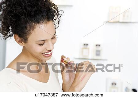 Woman testing lipstick on the back of her hand at the beauty counter of a store View Large Photo Image Stock Photo - Woman testing lipstick on the back of her hand at the beauty counter of a store. Fotosearch