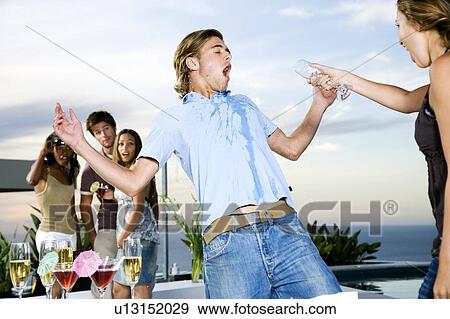 Stock Photo - Woman throwing her drink over a man at a party. Fotosearch