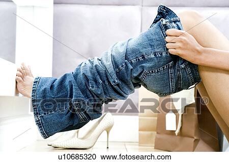 Stock Image - Woman trying on jeans in the changing room of a shop. Fotosearch