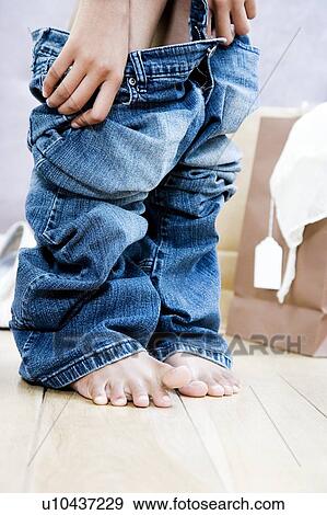Woman trying on jeans in the changing room of a shop View Large Photo Image Stock Photo - Woman trying on jeans in the changing room of a shop. Fotosearch