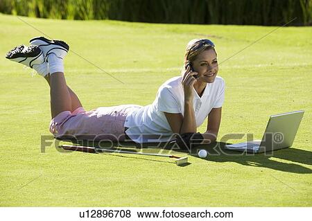Woman using a laptop and mobile phone whilst on the golf course View Large Photo Image Stock Photo - Woman using a laptop and mobile phone whilst on the golf course. Fotosearch