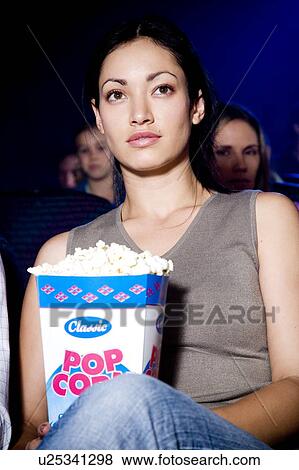 Stock Photo - Woman watching a film at the cinema. Fotosearch