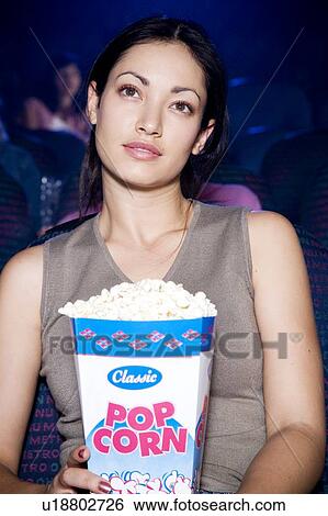 Stock Photograph - Woman watching a film at the cinema. Fotosearch