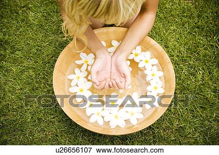Stock Photo - Woman with a bowl of floating frangipani in a tropical setting.. Fotosearch