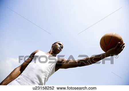 Young African American man holding out a basketball, arm outstretched View Large Photo Image Stock Image - Young African American man holding out a basketball, arm outstretched . Fotosearch