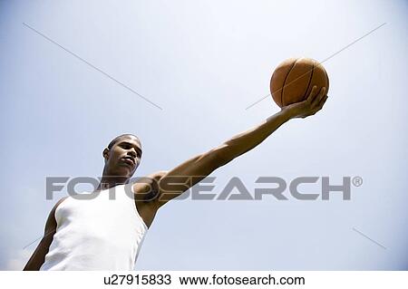Young African American man holding out a basketball, arm outstretched View Large Photo Image Stock Image - Young African American man holding out a basketball, arm outstretched . Fotosearch