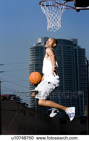 Young African American man jumping with a basketball on an urban basketball court View Large Photo Image Stock Image - Young African American man jumping with a basketball on an urban basketball court. Fotosearch