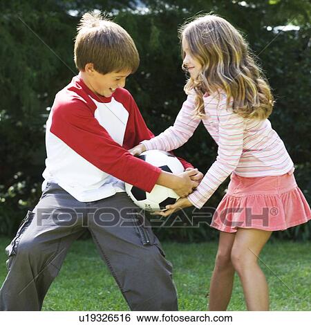 Stock Photograph - Young boy and girl playing with a football in a garden. Fotosearch