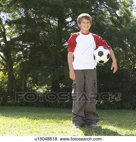 Young boy holding a football in a garden View Large Photo Image Stock Photo - Young boy holding a football in a garden. Fotosearch