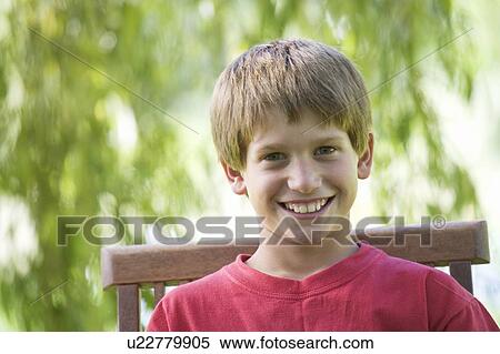 Young boy sitting in a garden chair, close-up View Large Photo Image Stock Photography - Young boy sitting in a garden chair, close-up. Fotosearch