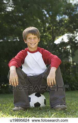 Picture - Young boy sitting on a football. Fotosearch