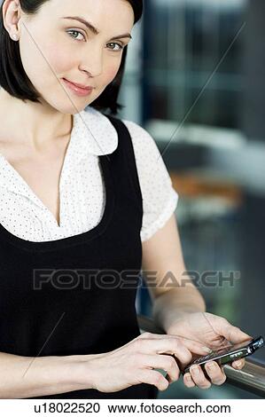 Young businesswoman in an office using a mobile phone View Large Photo Image Stock Image - Young businesswoman in an office using a mobile phone. Fotosearch