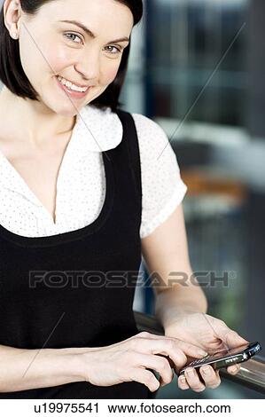 Stock Image - Young businesswoman in an office using a mobile phone. Fotosearch