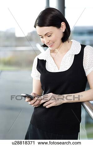 Young businesswoman in an office using a mobile phone View Large Photo Image Stock Image - Young businesswoman in an office using a mobile phone. Fotosearch