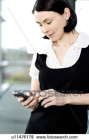 Stock Photo - Young businesswoman in an office using a mobile phone. Fotosearch