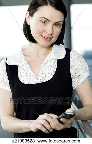 Young businesswoman in an office using a mobile phone View Large Photo Image Stock Photo - Young businesswoman in an office using a mobile phone. Fotosearch