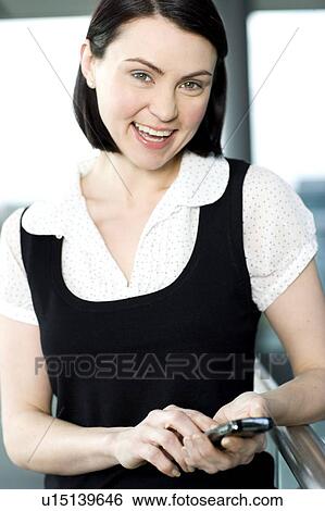 Young businesswoman in an office using a mobile phone View Large Photo Image Stock Photograph - Young businesswoman in an office using a mobile phone. Fotosearch