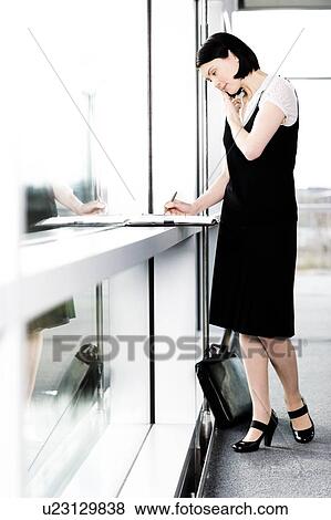 Stock Photo - Young businesswoman or secretary making an appointment in a diary. Fotosearch