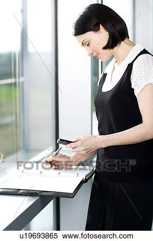 Stock Photography - Young businesswoman or secretary making an appointment in a diary. Fotosearch