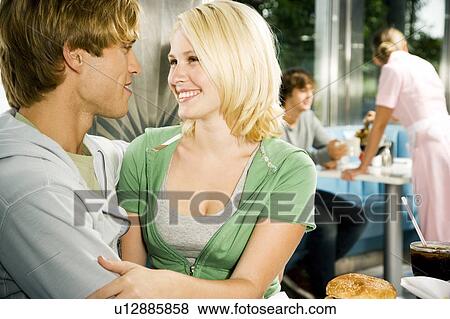 Stock Photo - Young couple about to kiss, sitting in a diner . Fotosearch