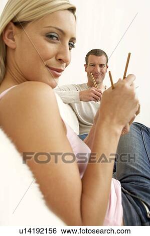 Stock Photograph - Young couple eating food with chopsticks. Fotosearch