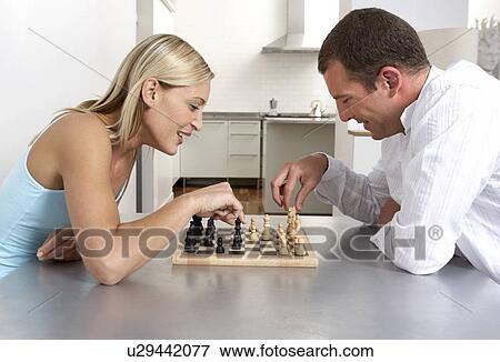 Young couple playing a game of chess in the kitchen View Large Photo Image Stock Photo - Young couple playing a game of chess in the kitchen. Fotosearch