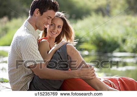 Stock Photo - Young couple sitting in the sun. Fotosearch