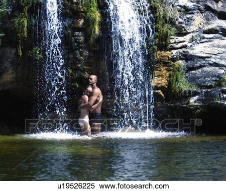 Stock Photography - Young couple standing in a waterfall, embracing. Fotosearch