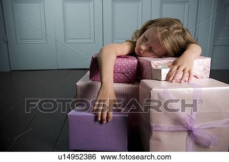 Stock Photograph - Young girl asleep and laying on her with birthday presents . Fotosearch