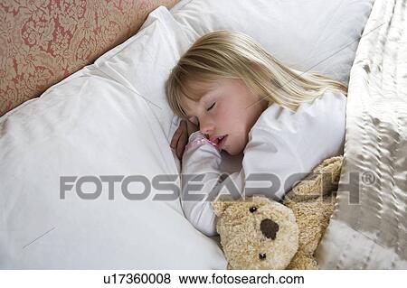 Stock Photo - Young girl asleep in her bed with a teddy bear . Fotosearch