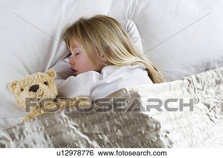 Young girl asleep in her bed with a teddy bear View Large Photo Image Stock Photograph - Young girl asleep in her bed with a teddy bear . Fotosearch
