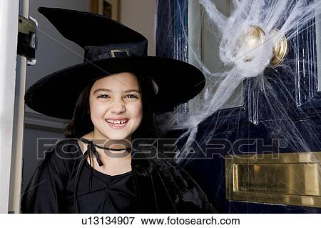 Stock Photo - Young girl at the front door, dressed up as a witch for Halloween . Fotosearch