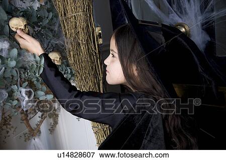 Stock Photo - Young girl at the front door, dressed up as a witch for Halloween . Fotosearch