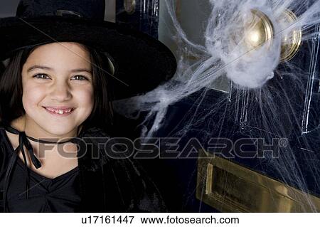 Stock Photo - Young girl at the front door, dressed up as a witch for Halloween . Fotosearch