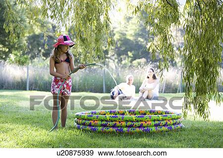 Young girl filling a paddling pool from a garden hose View Large Photo Image Stock Photo - Young girl filling a paddling pool from a garden hose. Fotosearch